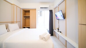 Habitación de hotel con cama, armario, aire acondicionado, televisor y ventana con cortinas.