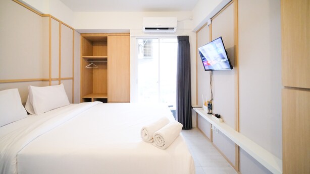 Habitación de hotel con cama, armario, aire acondicionado, televisor y ventana con cortinas.