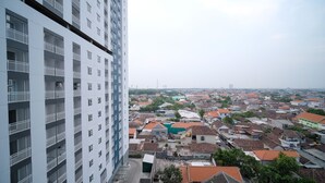 Un edificio de gran altura con múltiples balcones y vistas a una zona urbana densamente poblada, con diversos edificios y zonas verdes.