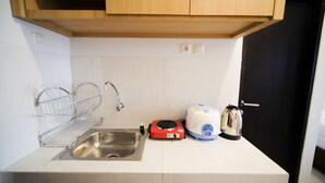 Una cocina pequeña con un lavamanos, un hervidor, un tostador y otro hervidor en la encimera.