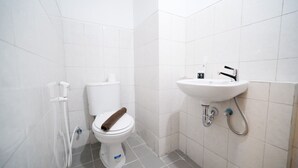 Un baño pequeño y limpio con inodoro blanco, lavamanos y ducha.