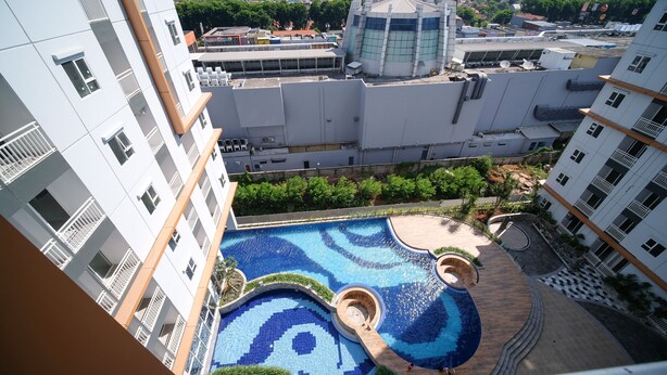 A rooftop swimming pool with a circular design, surrounded by multi-story residential buildings. - Comfy And Spacey 2Br Apartment At Suncity Residence (Sidoarjo)