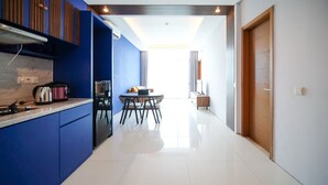 A modern kitchen with blue cabinetry, a dining area with a round table and chairs, and a view of a balcony. - Best Choice And Spacious 1Br Apartment At Aryaduta Residence Surabaya (Surabaya)