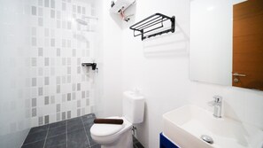 Bathroom features a toilet, sink, and shower area with a towel rack.
