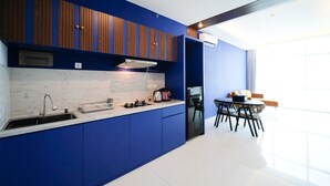 A modern kitchen with blue cabinetry, a white marble backsplash, and a dining area with a table and chairs. - Best Choice And Spacious 1Br Apartment At Aryaduta Residence Surabaya (Surabaya)