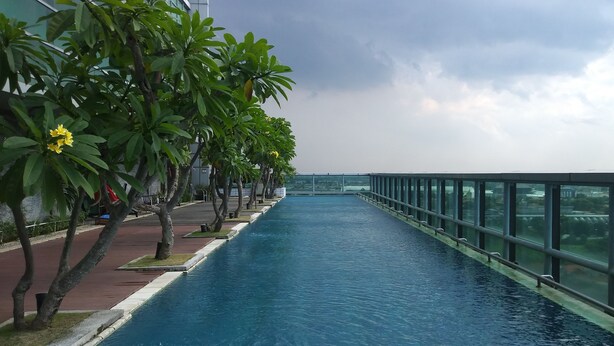 A long, narrow water feature flanked by trees and a glass railing. - Best Choice And Spacious 1Br Apartment At Aryaduta Residence Surabaya (Surabaya)
