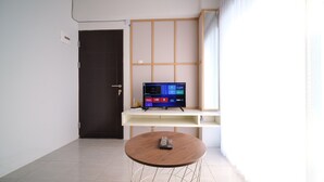 Uma sala de estar moderna com uma TV sobre um móvel, uma mesa de madeira e uma porta.