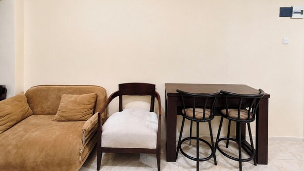 Una sala de estar con un sofá, una silla y una mesa de comedor con dos sillas.