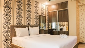 A neatly made bed with white linens and pillows, a wooden headboard, and a large mirror above it. - Spacious Studio At Gateway Ahmad Yani Cicadas Apartment (Bandung)