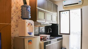 A compact kitchen with a refrigerator, a water dispenser, a microwave, and a small sink. - Spacious Studio At Gateway Ahmad Yani Cicadas Apartment (Bandung)