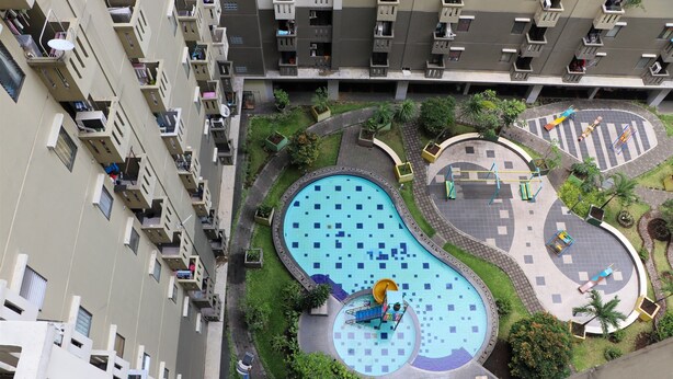 A residential building with multiple balconies, a swimming pool, and a playground area. - Spacious Studio At Gateway Ahmad Yani Cicadas Apartment (Bandung)