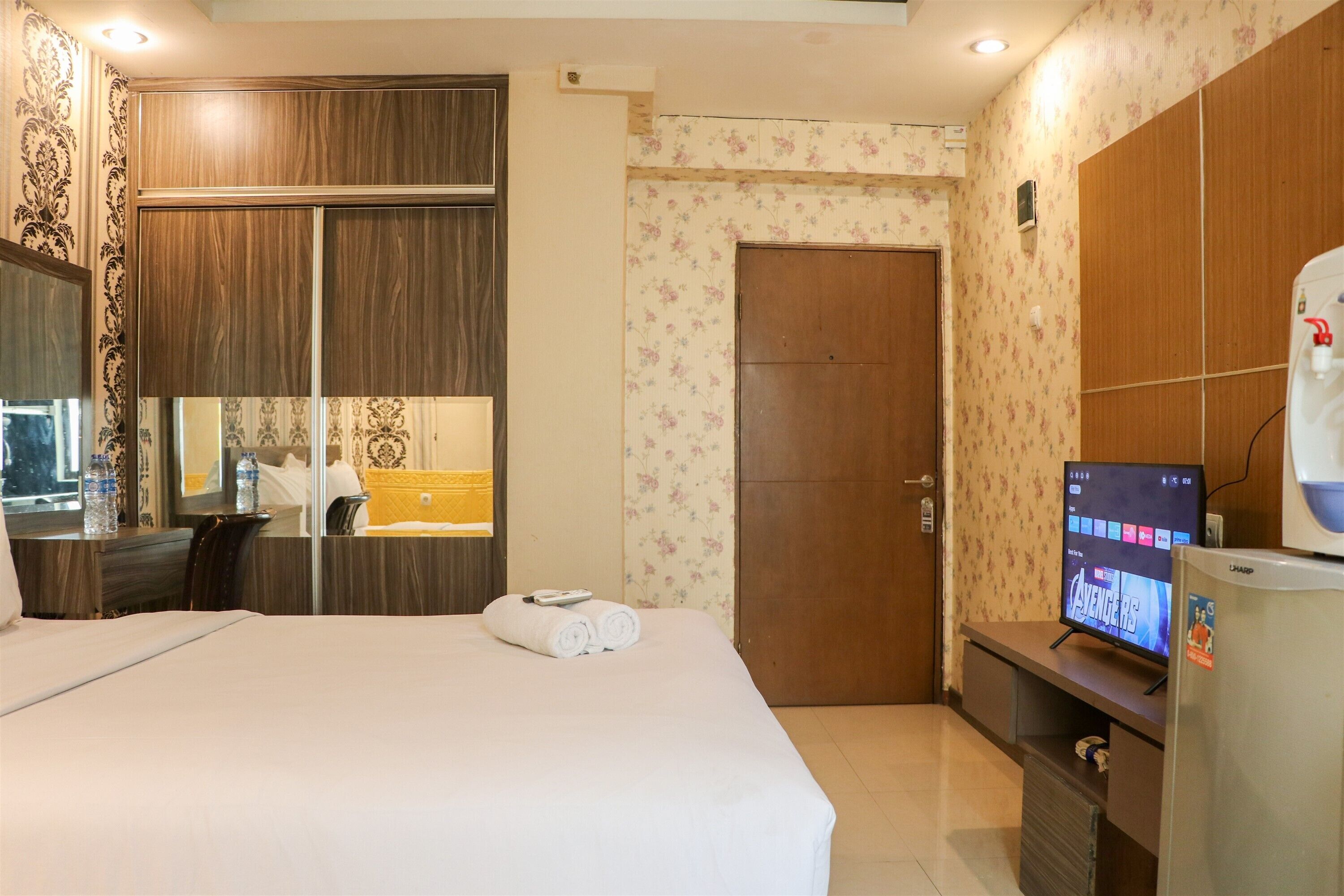 Habitación de hotel con cama, televisión, armario y baño.