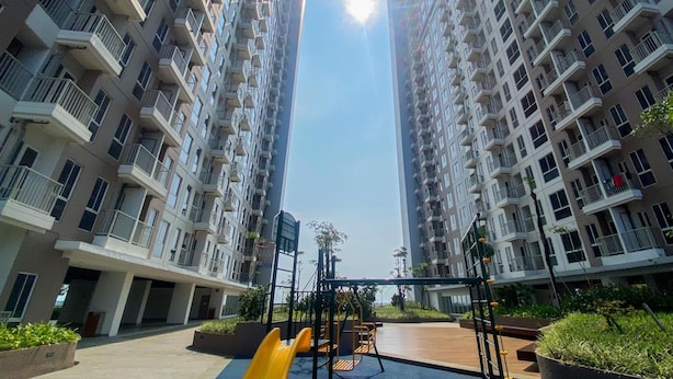 A high-rise residential building with multiple balconies and a central courtyard with playground equipment. - Comfortable 2Br At Tokyo Riverside Pik 2 Apartment (Teluknaga)