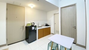A compact kitchen with a refrigerator, sink, and wooden cabinets. - Comfortable 2Br At Tokyo Riverside Pik 2 Apartment (Teluknaga)