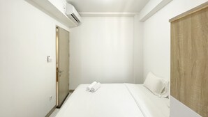A hotel room with a bed, a wooden wardrobe, and an air conditioning unit. - Comfortable 2Br At Tokyo Riverside Pik 2 Apartment (Teluknaga)