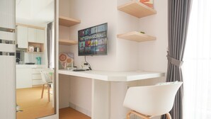 A modern kitchen with a built-in TV, white cabinetry, and a wooden dining table. - Comfort And Enjoy Living Studio Casa De Parco Apartment (Pagedangan)