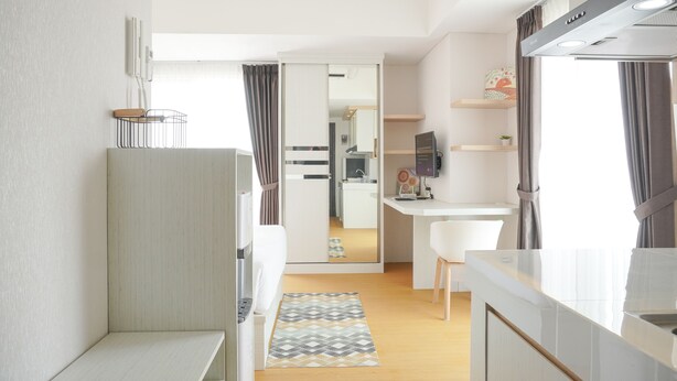 A modern kitchen with a white countertop, a built-in stove, and a dining area with a white chair and table. - Comfort And Enjoy Living Studio Casa De Parco Apartment (Pagedangan)