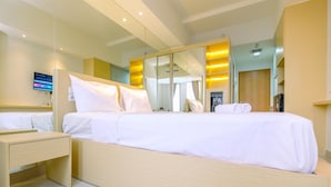 Une chambre d’hôtel moderne dotée d’un grand lit, d’une table de chevet, d’une armoire avec des miroirs et d’un téléviseur à écran plat fixé au mur.
