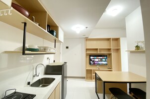 Una cocina moderna con un lavamanos, refrigerador y un televisor de pantalla plana montado en la pared.