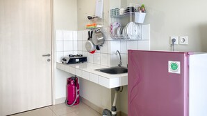 A compact kitchen with a white countertop, a pink refrigerator, and a gas stove.