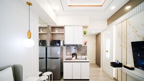 A modern kitchen with stainless steel appliances, white cabinetry, and a built-in oven. There is a small island with a coffee maker and a sink. - Modern And Cozy Studio At Benson Supermall Mansion Apartment (Surabaya)