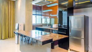 A modern kitchen with a granite countertop, stainless steel appliances, and a built-in oven. - Homey Penthouse 3Br With Extra Room Kemang Village Apartment (Jakarta)
