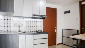 A modern kitchen with white cabinets, a black countertop, and a tiled backsplash. - Spacious 3Br With Good View At Gateway Pasteur Apartment (Cimahi)