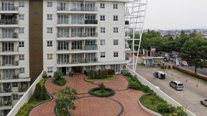 A multi-story residential building with a central courtyard, balconies, and a parking area with a gas station in the background. - Spacious 3Br With Good View At Gateway Pasteur Apartment (Cimahi)