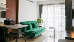 A modern living room with a green sofa, a dining table, and a TV. - Spacious 3Br With Good View At Gateway Pasteur Apartment (Cimahi)
