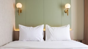 A bed with white linens and two wall-mounted light fixtures. - Brand New 2Br At Tamansari Panoramic Apartment (Bandung)