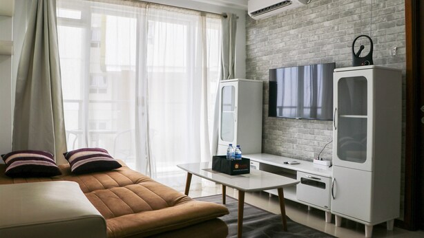 Una sala de estar moderna con un sofá, un televisor de pantalla plana, un armario blanco y un equipo de aire acondicionado en la pared.