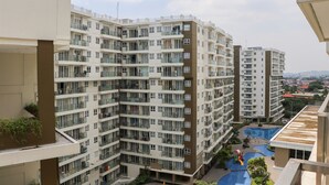 Un edificio residencial de gran altura con múltiples balcones, una piscina en la azotea y vistas del entorno.