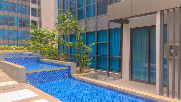 A modern building with a swimming pool, surrounded by greenery and large windows. - Best Spacious And Nice 3Br At 28Th Floor Casa Grande Apartment (Jakarta)