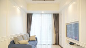 A modern living room with a sofa, a TV, and a small table. - Best Spacious And Nice 3Br At 28Th Floor Casa Grande Apartment (Jakarta)