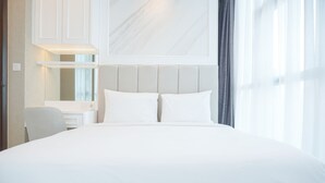 A large bed with white bedding, a headboard, a bedside table with a lamp, and a mirror. - Best Spacious And Nice 3Br At 28Th Floor Casa Grande Apartment (Jakarta)