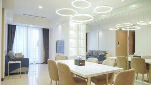 A modern hotel room with a dining area, a sofa, and a large mirror. - Best Spacious And Nice 3Br At 28Th Floor Casa Grande Apartment (Jakarta)
