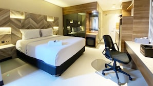 Een moderne hotelkamer met een groot bed, een bureau en een stoel.
