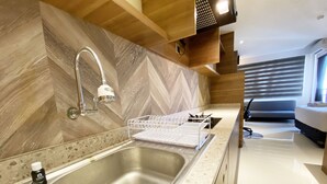Een moderne keuken met een roestvrijstalen spoelbak, een houten visgraat achterwand en een inbouwoven.