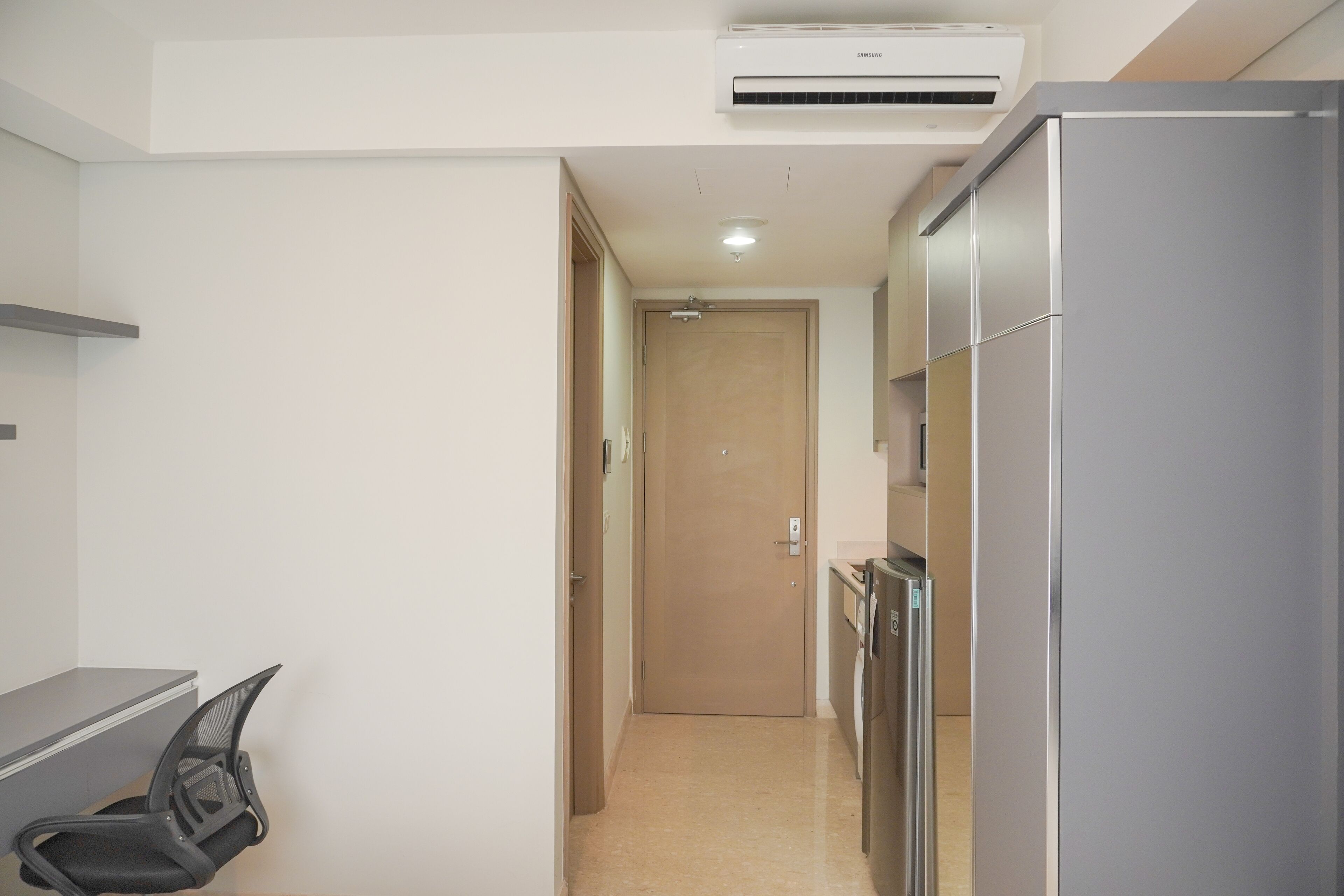A narrow hallway with a kitchenette area, including a refrigerator and a microwave.