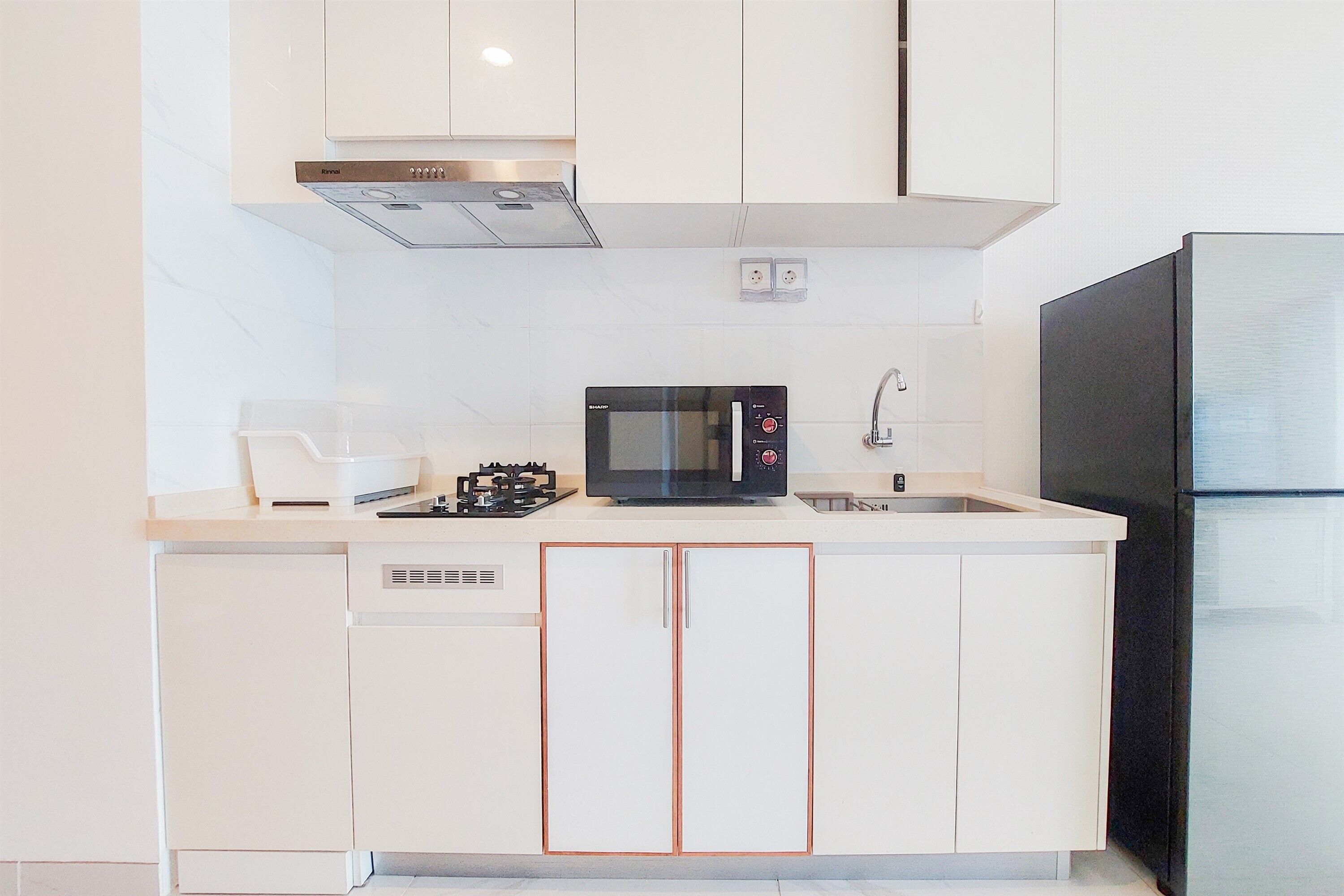 Eine moderne Küche mit weißen Schränken, einer schwarzen Mikrowelle, einem eingebauten Backofen und einem schwarzen Kühlschrank.