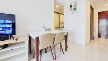 A modern hotel room with a dining area, a flat-screen TV, and a bathroom visible in the background.