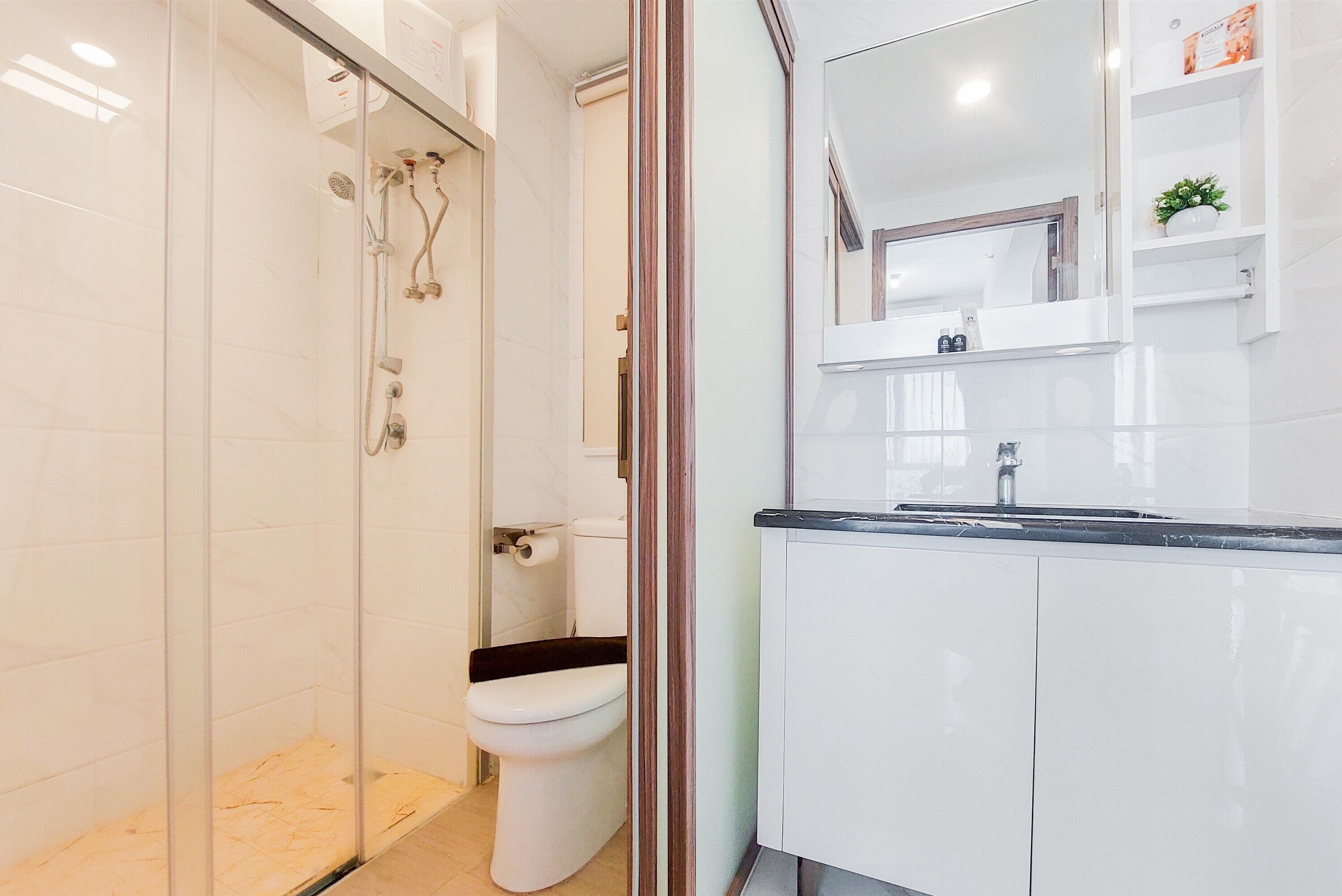 A modern bathroom with a glass-enclosed shower, a toilet, and a vanity with a mirror and shelves.