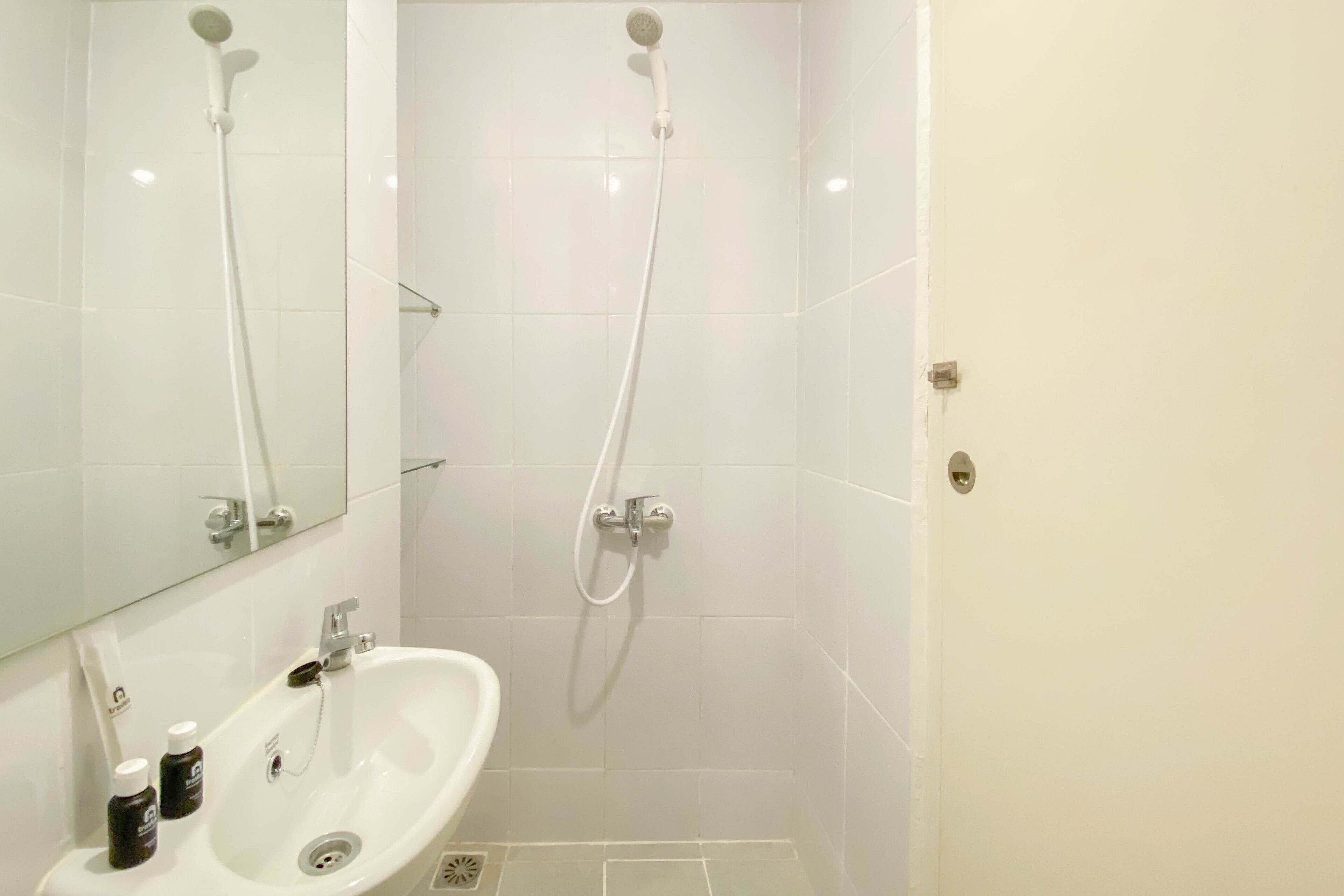 Un baño con lavamanos, espejo y ducha blancos.
