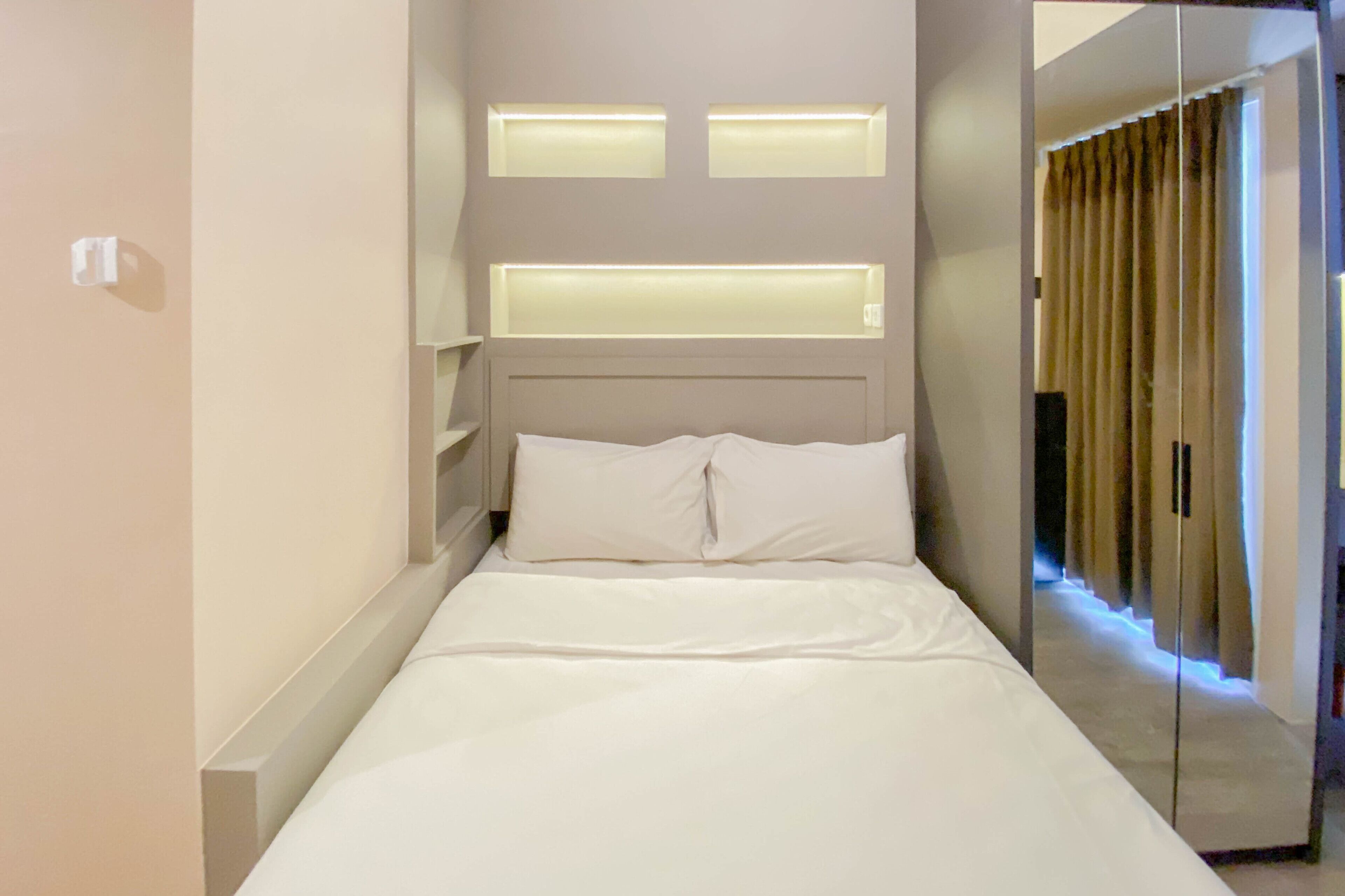 A neatly made bed with white linens in a modern hotel room.