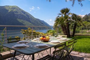 An outdoor dining table set with plates, cutlery, and a fruit bowl, overlooking a mountainous landscape. - Il Tentione, Valsolda, Italy (Valsolda)