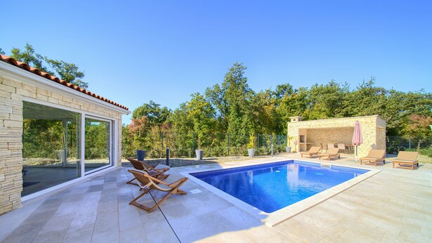A modern outdoor pool area with a stone building, lounge chairs, and a clear view of the surrounding trees. - Villa Amarie (Kvarner - Risika) (Risika)