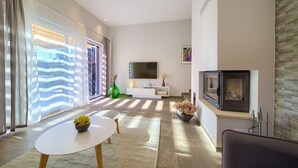 A modern living room with a fireplace, a flat-screen TV, and a large window with sheer curtains. - Villa Amarie (Kvarner - Risika) (Risika)