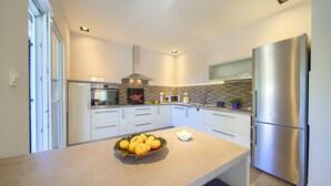 A modern kitchen with white cabinets, a stainless steel refrigerator, and a bowl of oranges on the counter. - Villa Amarie (Kvarner - Risika) (Risika)