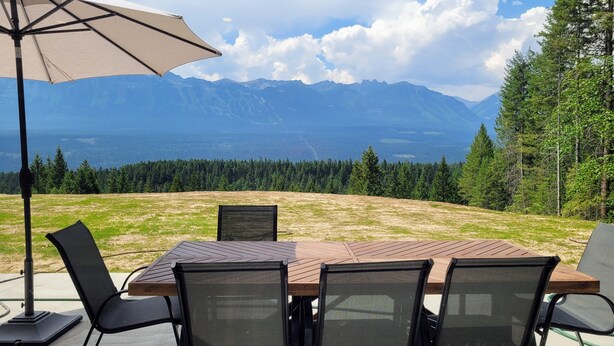 A table and chairs set outdoors with a mountain view in the background. - Stay Golden - Monashee House (Golden)