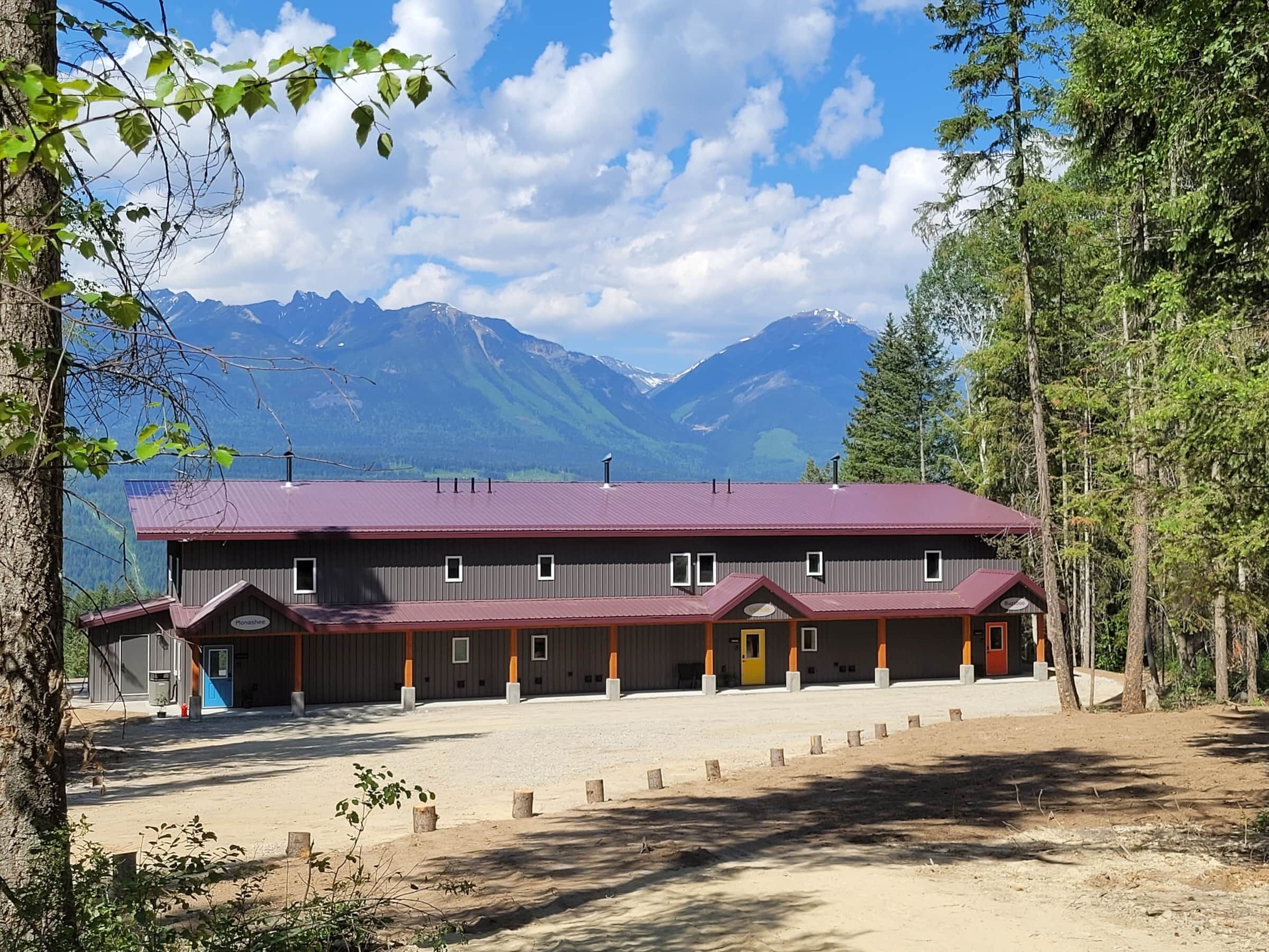 A lodge with a red roof, multiple rooms, and a view of mountains.